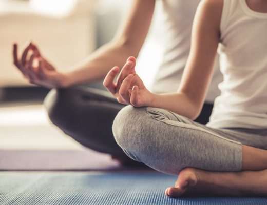 Cropped image of young woman and her little daughter doing yoga together at home